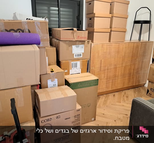 ערימת קרטונים מסודרת בחדר עם מחיצה מעץ